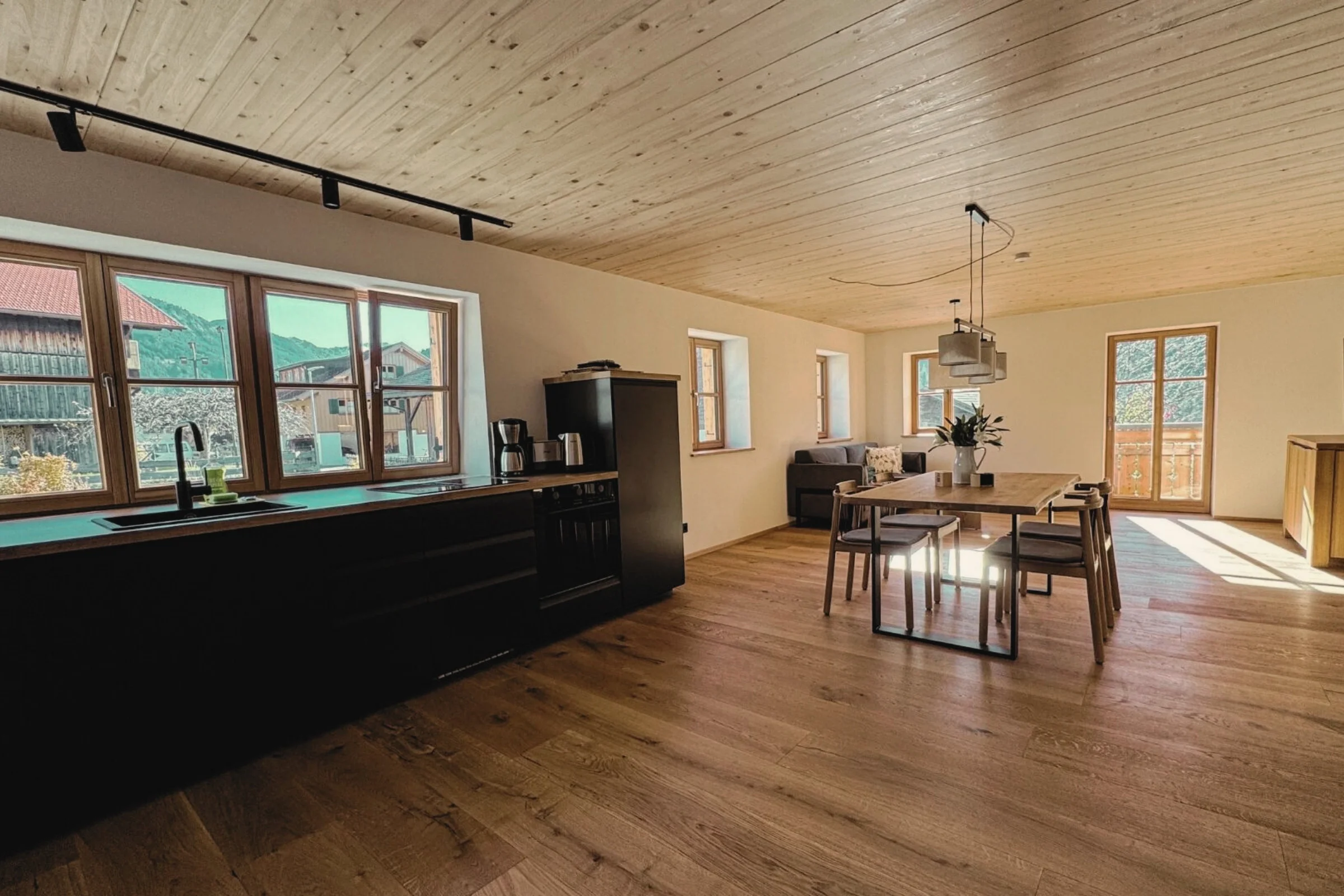 Offener Wohn-Essbereich mit Küche, Holzdecke und Bergblick in der Alpenherz Suite