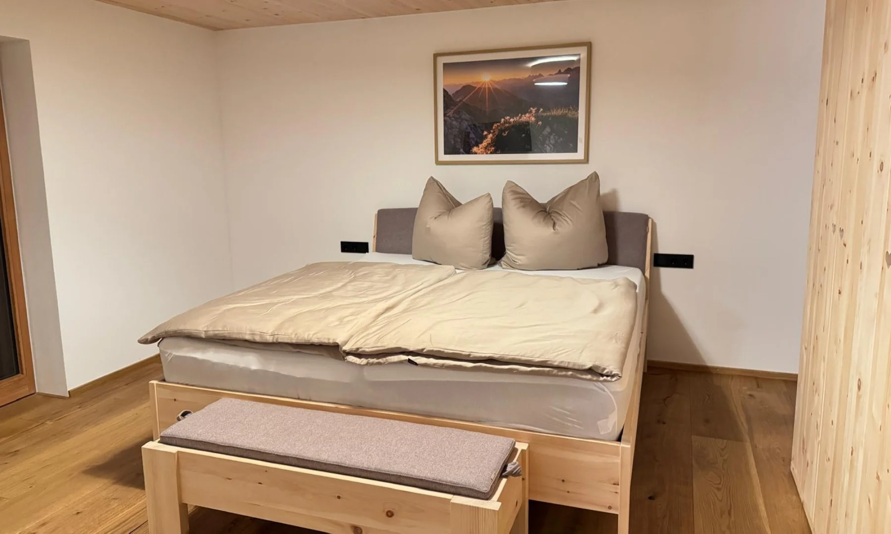 Romantisches Schlafzimmer der Zirben Suite mit Doppelbett aus Zirbenholz und Bergbild