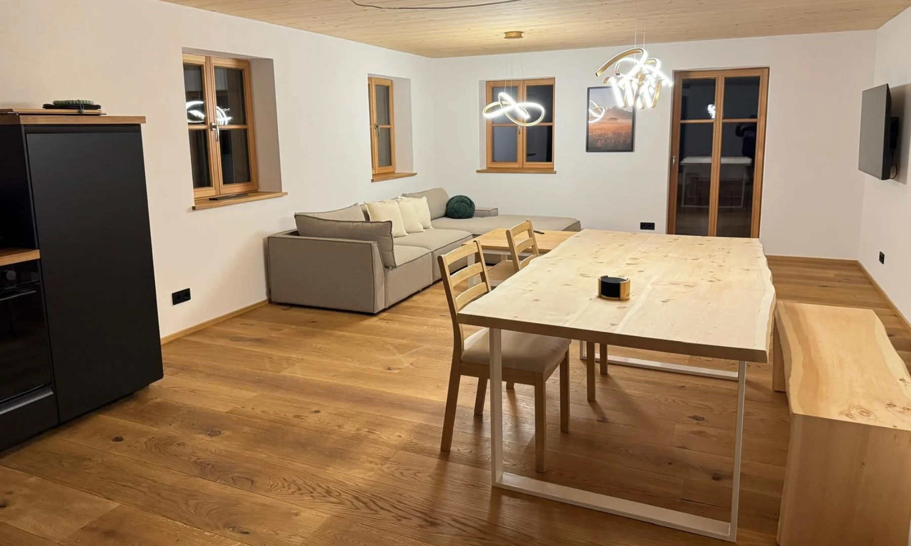 Offener Wohn-Essbereich der Zirben Suite mit Massivholztisch, Sofa und Holzdecke