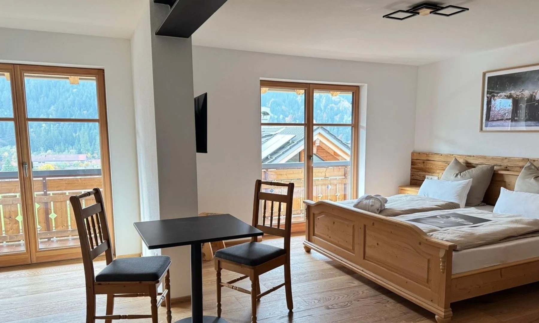 Schlaf-Wohnbereich mit Holzbett, Essplatz und Bergblick in der Alpenschein Wohnung