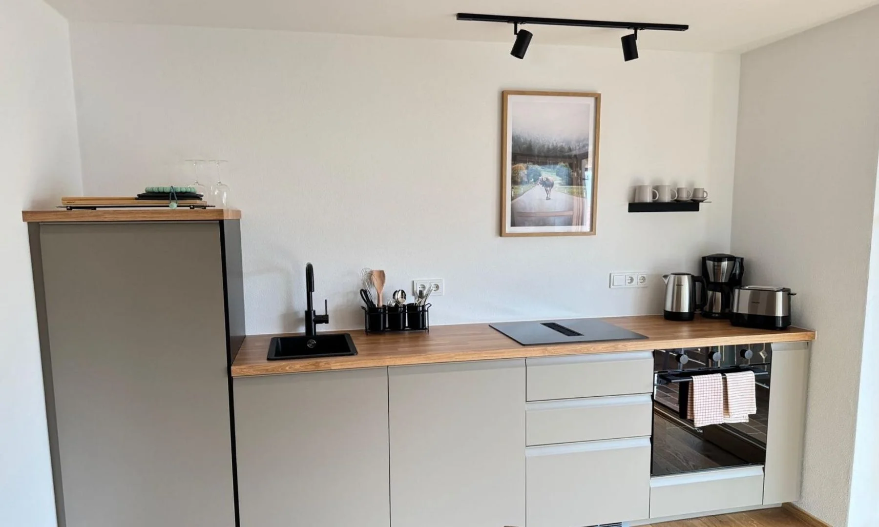 Moderne Premium-Küche mit Holzarbeitsplatte, Induktionsfeld, Backofen und Kaffeemaschine