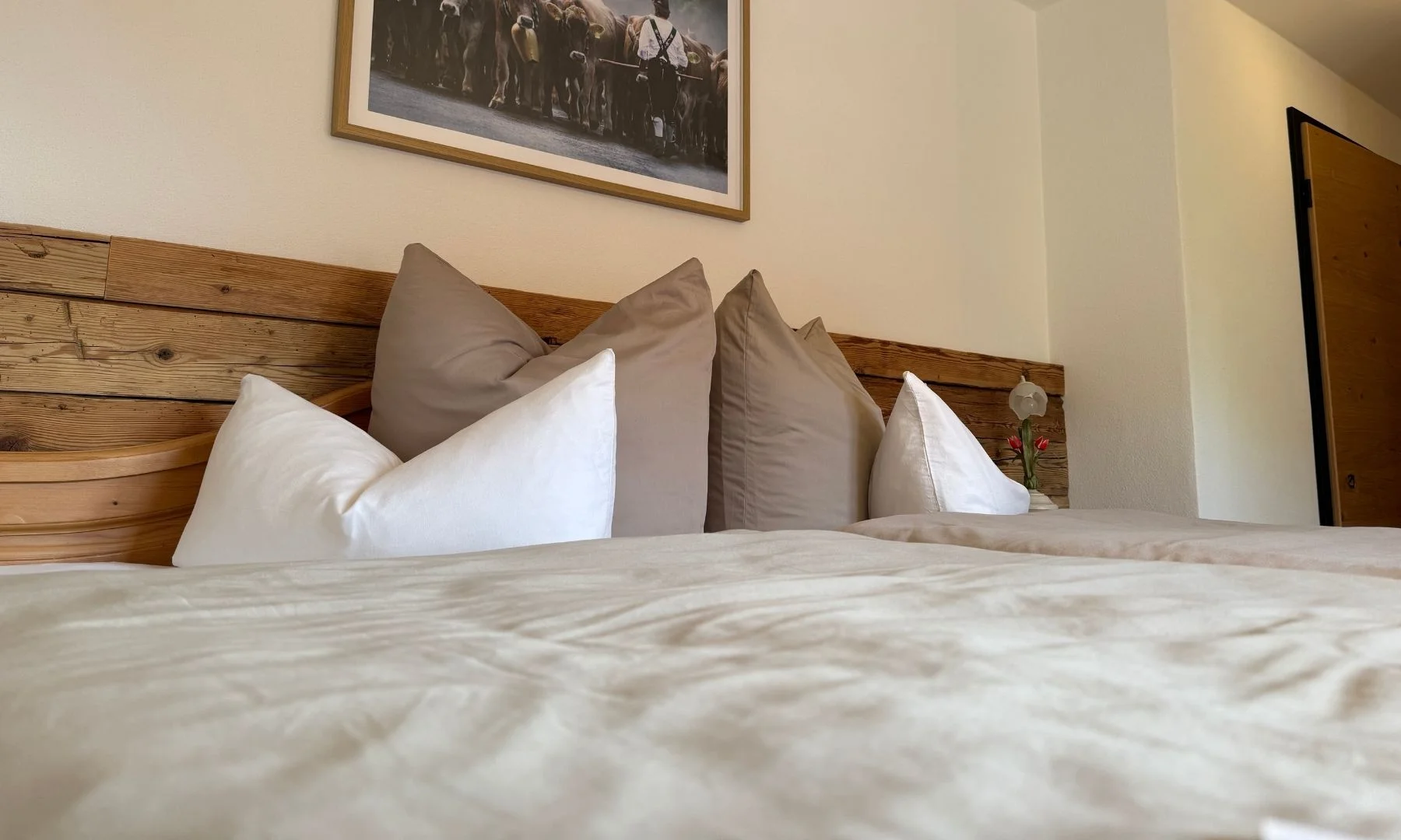 Doppelbett mit weißen und beigen Kissen vor Altholz-Kopfteil im Wohn-Schlafbereich