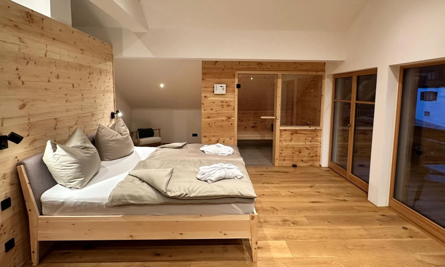 Schlafzimmer der Panorama Suite mit Holzwänden, Doppelbett und eigener Zirben-Sauna